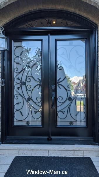 Black Double front door. Curved transom. Round top. Rochester wrought iron glass inserts